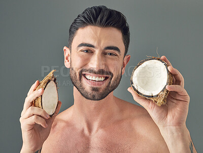 Buy stock photo Studio shot of a handsome young man holding up a coconut