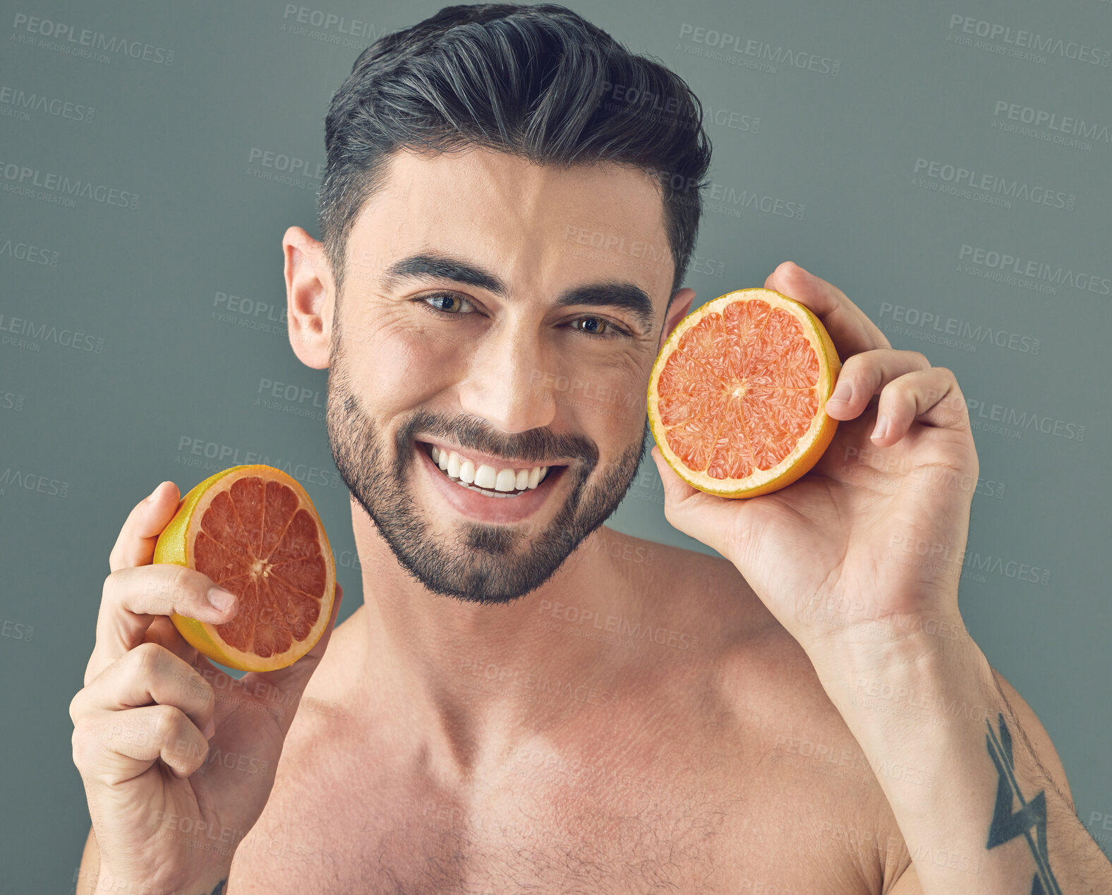 Buy stock photo Studio shot of a handsome young man holding up a grapefruit