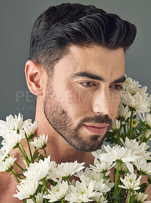 Buy stock photo Studio shot of a handsome young man posing with flowers against a grey background