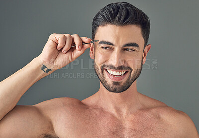 Buy stock photo Shot of a handsome young man tweezing his eyebrows