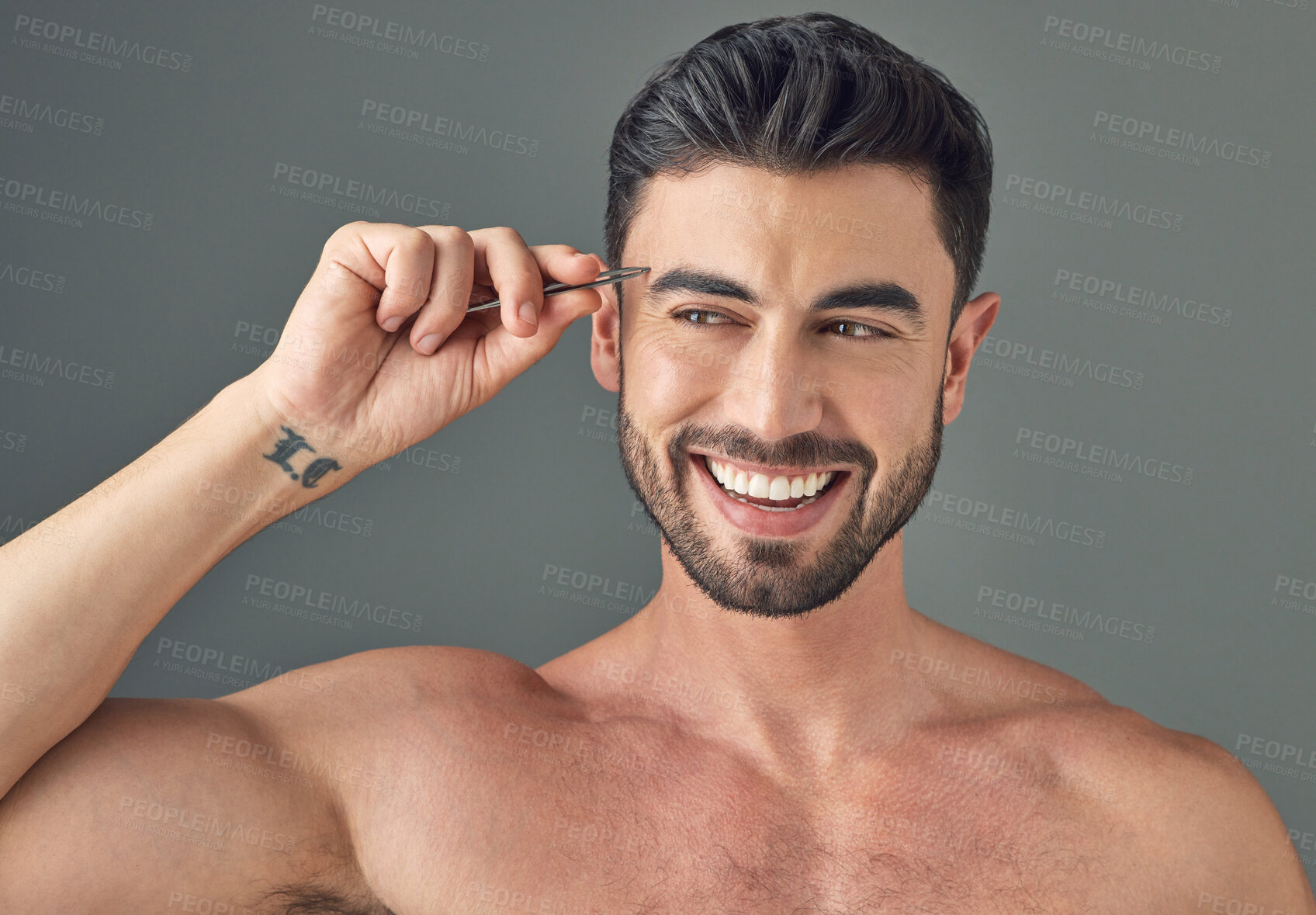 Buy stock photo Shot of a handsome young man tweezing his eyebrows