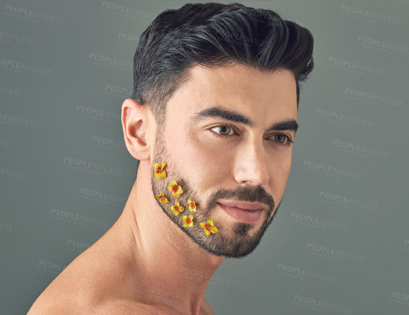 Buy stock photo Studio shot of a handsome young woman posing with flowers in his beard