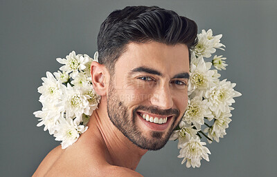 Buy stock photo Studio shot of a handsome young man posing with flowers against a grey background