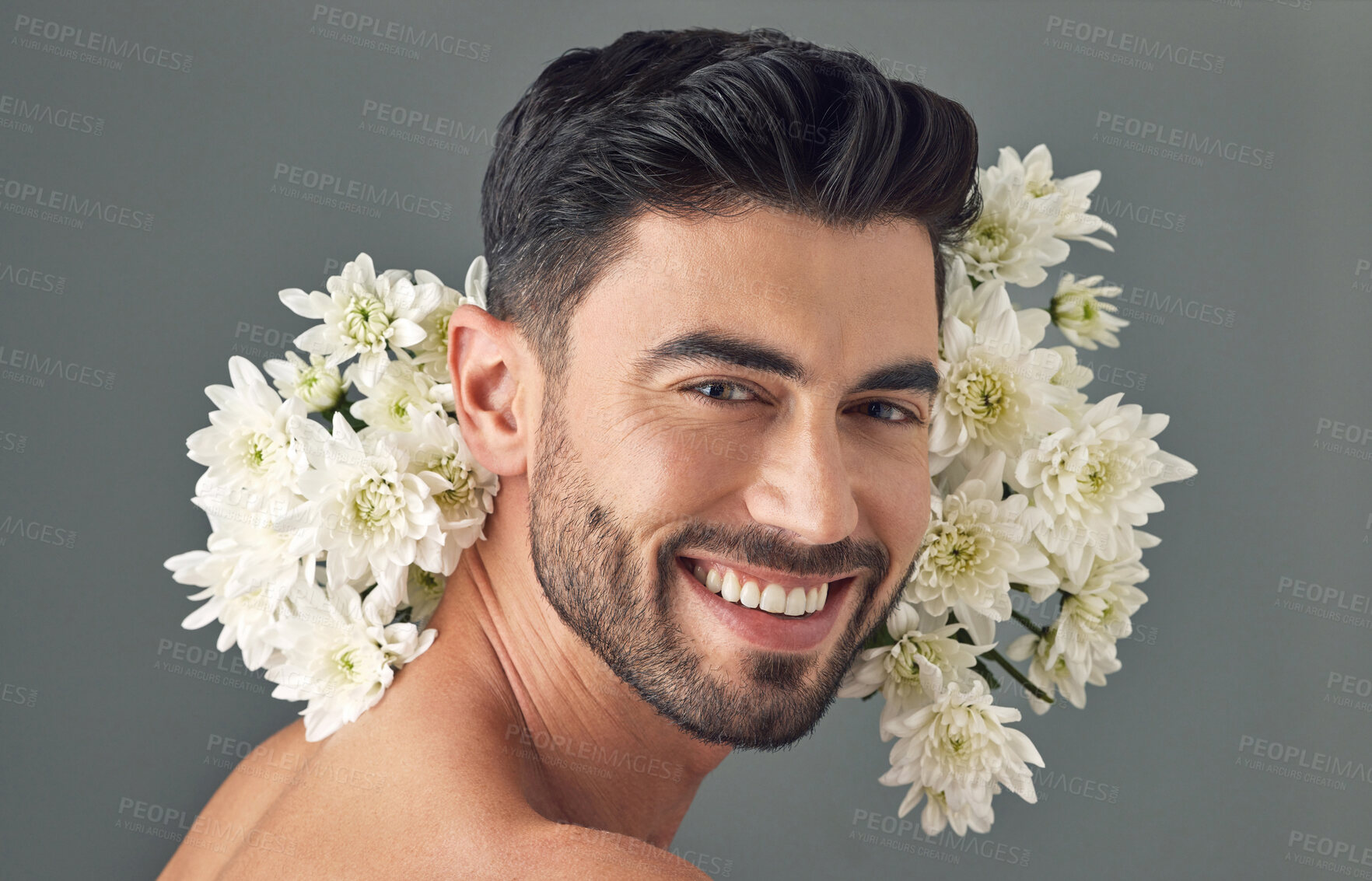 Buy stock photo Studio shot of a handsome young man posing with flowers against a grey background