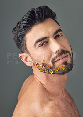 Buy stock photo Studio shot of a handsome young woman posing with flowers in his beard