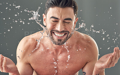 Buy stock photo Shot of a handsome young wan washing his face while standing against a grey background