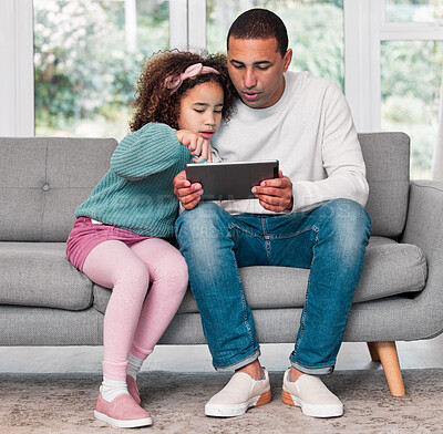 Buy stock photo Shot of a little girl and her father using a digital tablet together at home