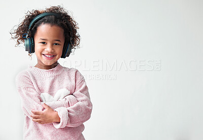 Buy stock photo Portrait, girl and kid with headphones, arms crossed and streaming music on white studio background. Face, childhood and model with headset, sound and audiobook with song, joy and listening to radio