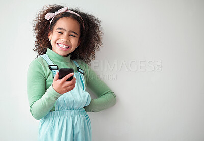 Buy stock photo Girl, white background and smile on smartphone with headphones for streaming music or playlist. Kid, audio and happy in portrait on internet, online and mobile app for entertainment on mockup space