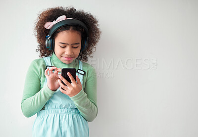 Buy stock photo Headphones, music and kid with phone in studio for streaming education podcast. Mobile, audio or girl child listening to sound, gaming app or online learning isolated on white background mockup space