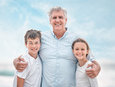 Buy stock photo Shot of a mature man and his grandchildren bonding at the beach