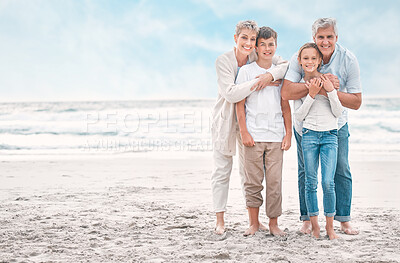 Buy stock photo Shot of a mature couple bonding with their grandchildren at the beach