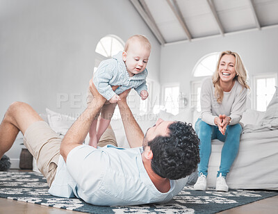 Buy stock photo Family, baby and playful with a father and daughter having fun in the living room with mom sitting on the sofa. Love, floor and happy with a man, girl and woman bonding together in their home
