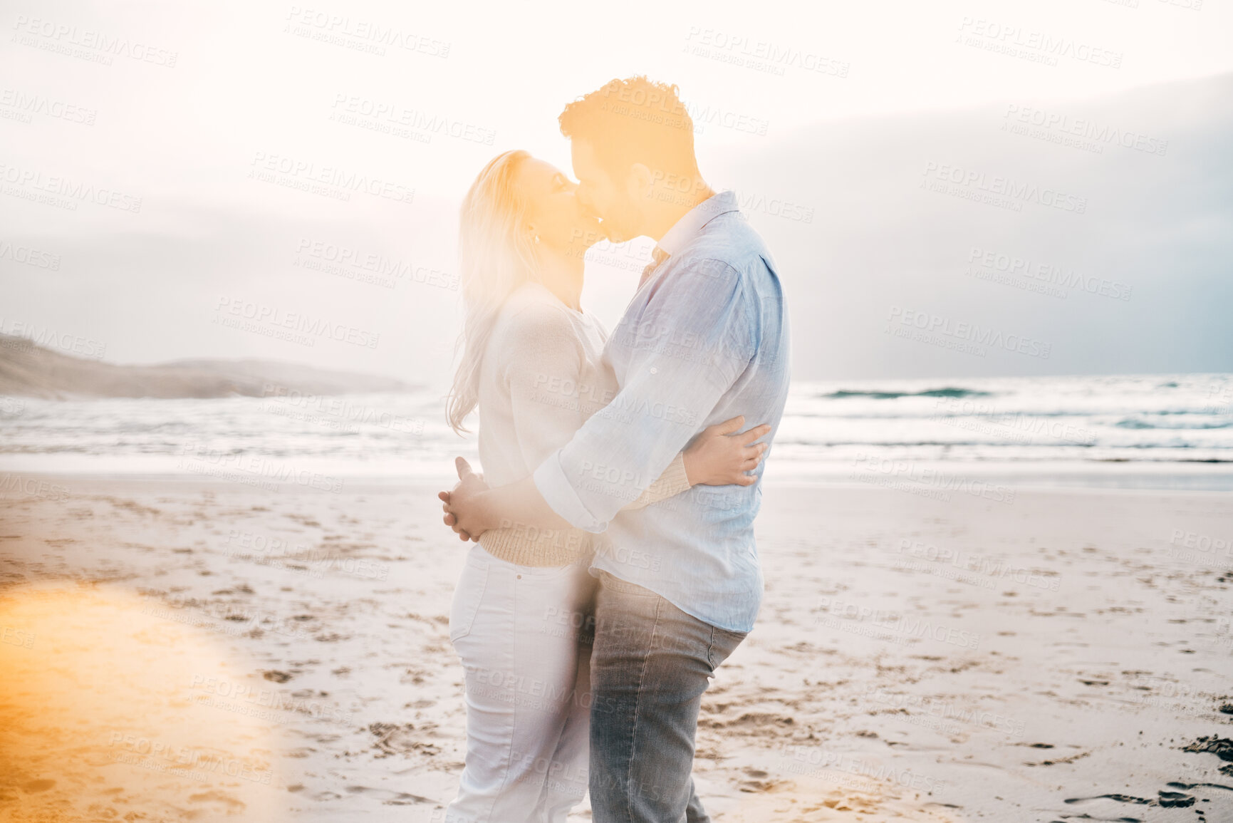 Buy stock photo Beach, lens flare and couple kiss for love on holiday, vacation and romantic weekend for anniversary. Travel, marriage and mature man kissing woman for bonding, quality time and happiness by ocean