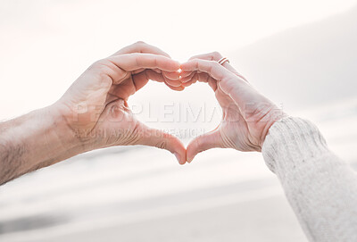 Buy stock photo Beach, couple and heart hands for love, support and care on holiday outdoor closeup. Romance, man and woman with sign at ocean for healthy relationship, connection and commitment together in summer