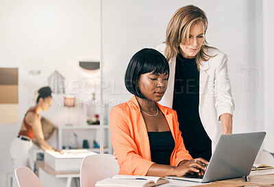 Buy stock photo Shot of a two businesswomen using a laptop together at work