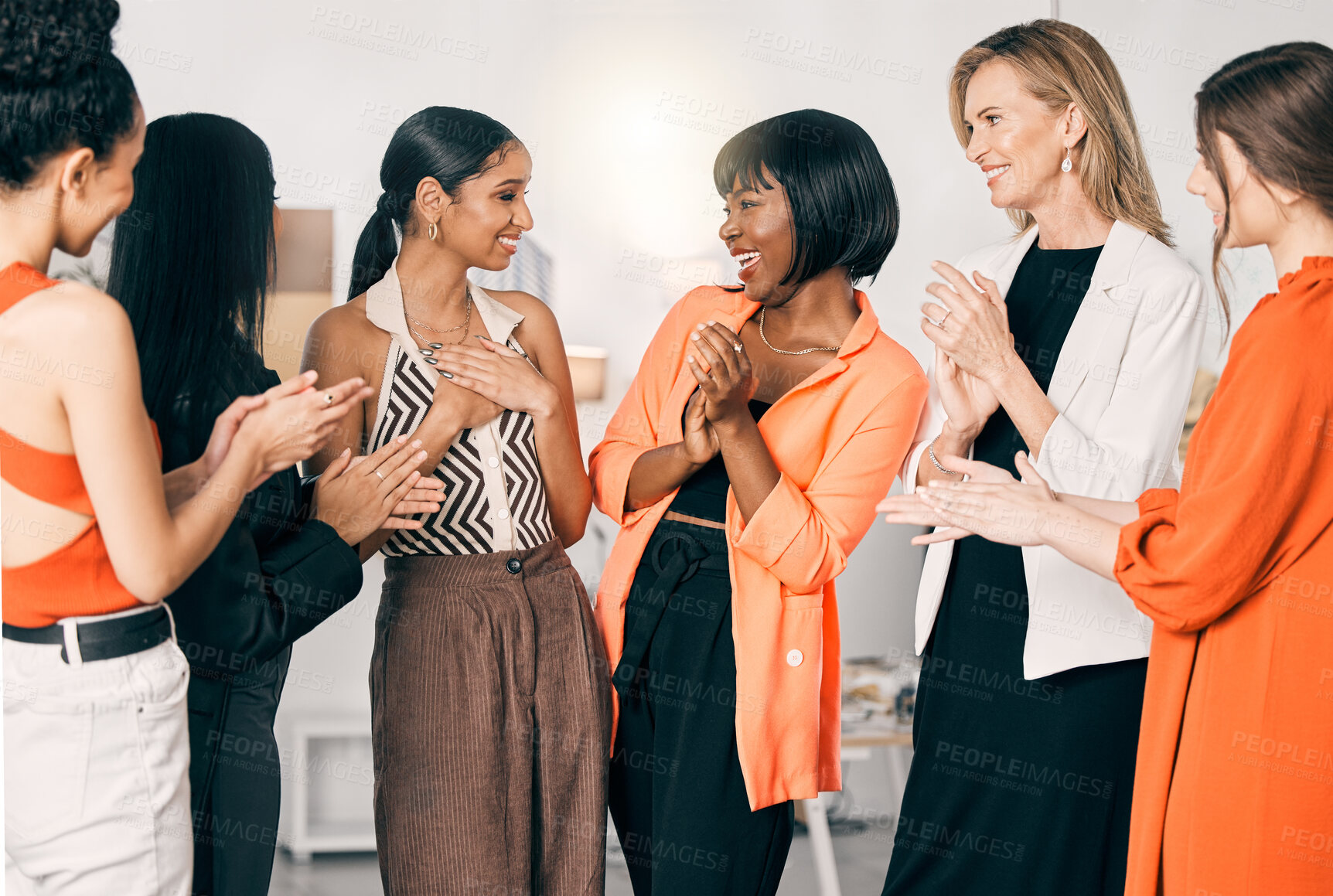 Buy stock photo Shot of a group of young businesswomen clapping for a coworker at work