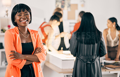 Buy stock photo Shot of a young woman standing with her arms crossed while her coworkers collaborate in the background