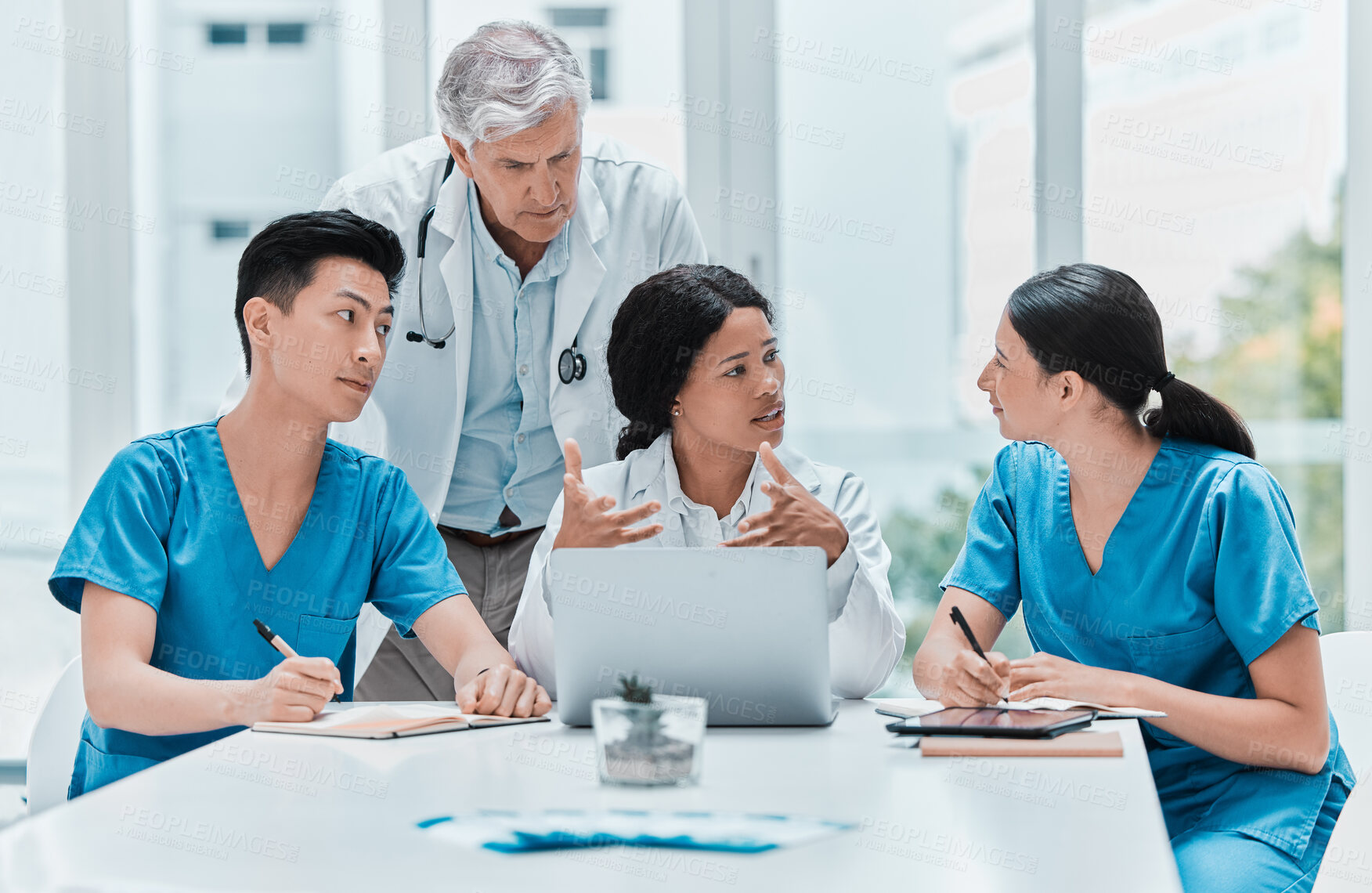 Buy stock photo Shot of a group of medical practitioners working together on a laptop in a medical office