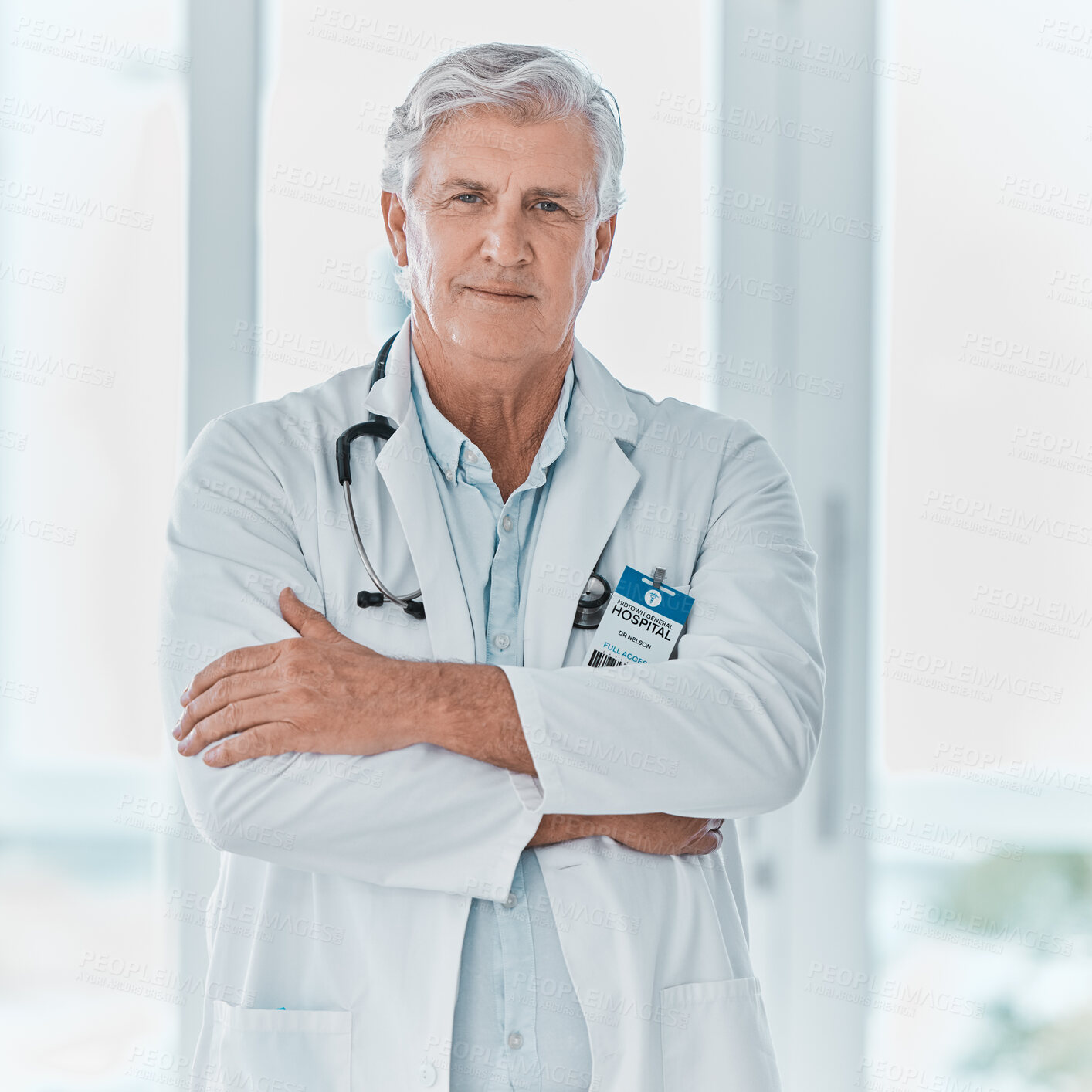 Buy stock photo Portrait of a mature doctor standing with his arms crossed in a hospital