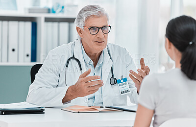 Buy stock photo Shot of a mature doctor sitting with his patient during a consultation in his clinic
