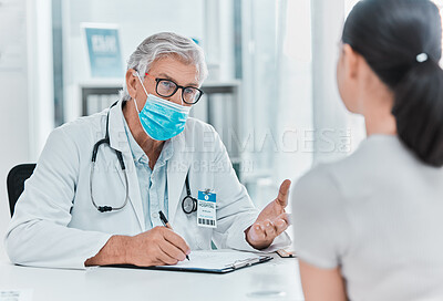 Buy stock photo Shot of a mature doctor wearing a face mask and sitting with his patient during a consultation in his clinic