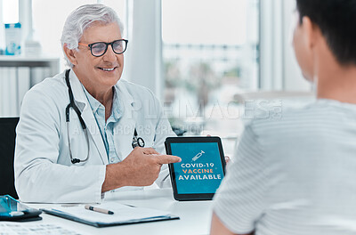 Buy stock photo Shot of a mature doctor sitting with his patient and using a digital tablet to discuss the availability of the Covid vaccine