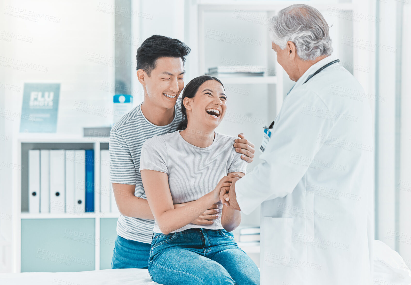 Buy stock photo Shot of a young couple talking to their doctor