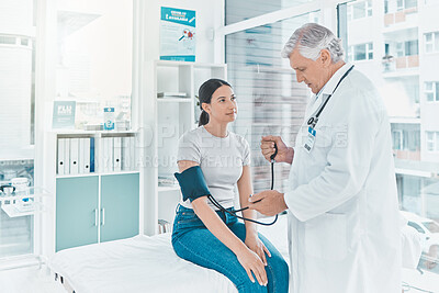 Buy stock photo Shot of a mature doctor checking a patients blood pressure
