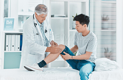 Buy stock photo Shot of a mature doctor checking his patients knee for injury