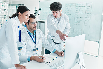 Buy stock photo Shot of a group of scientists working together on a computer in a lab