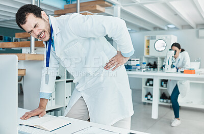 Buy stock photo Shot of a young scientist experiencing back pain while working in a lab