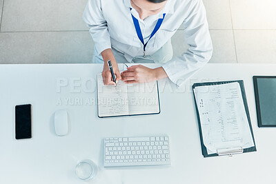 Buy stock photo High angle shot of an unrecognisable scientist writing notes while working on a computer in a lab