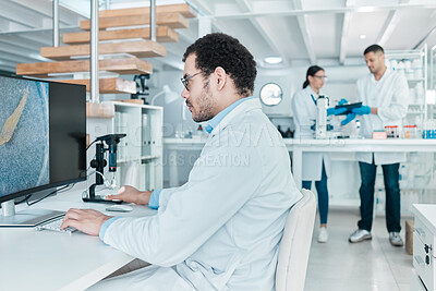 Buy stock photo Shot of a young scientist using a digital microscope while working on a computer in a lab