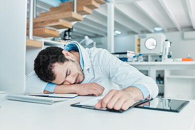 Buy stock photo Shot of a young scientist sleeping at a desk in a lab