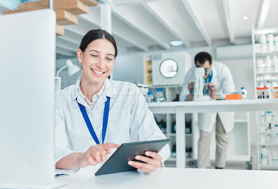 Buy stock photo Shot of a young scientist working on a digital tablet and computer in a lab