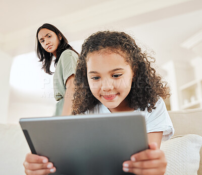 Buy stock photo Shot of a young woman watching her daughter using a digital tablet at home