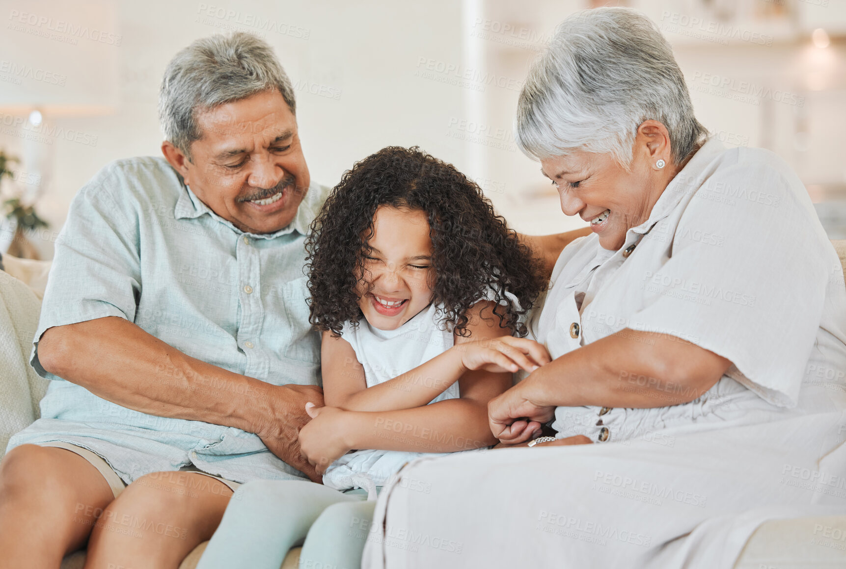 Buy stock photo Happy, grandparents and tickling child in home for funny joke, playful and bonding on weekend. Family, house and game with girl on sofa for retirement, humor and laughter in connection together