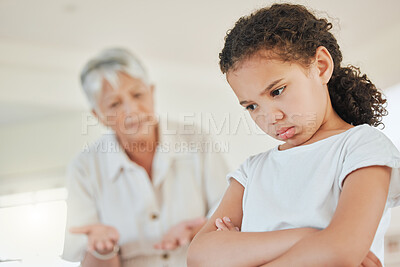 Buy stock photo Shot of a mature woman looking annoyed with her granddaughter at home
