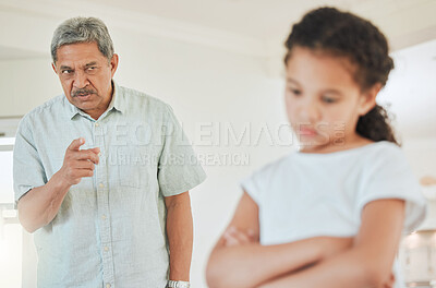 Buy stock photo Shot of a mature man looking annoyed with his granddaughter at home