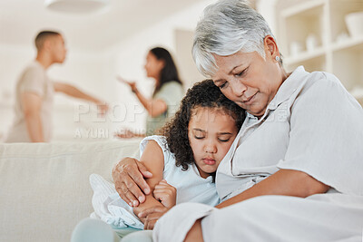 Buy stock photo Shot of a mature woman comforting her granddaughter on the sofa while her parents argue in the background