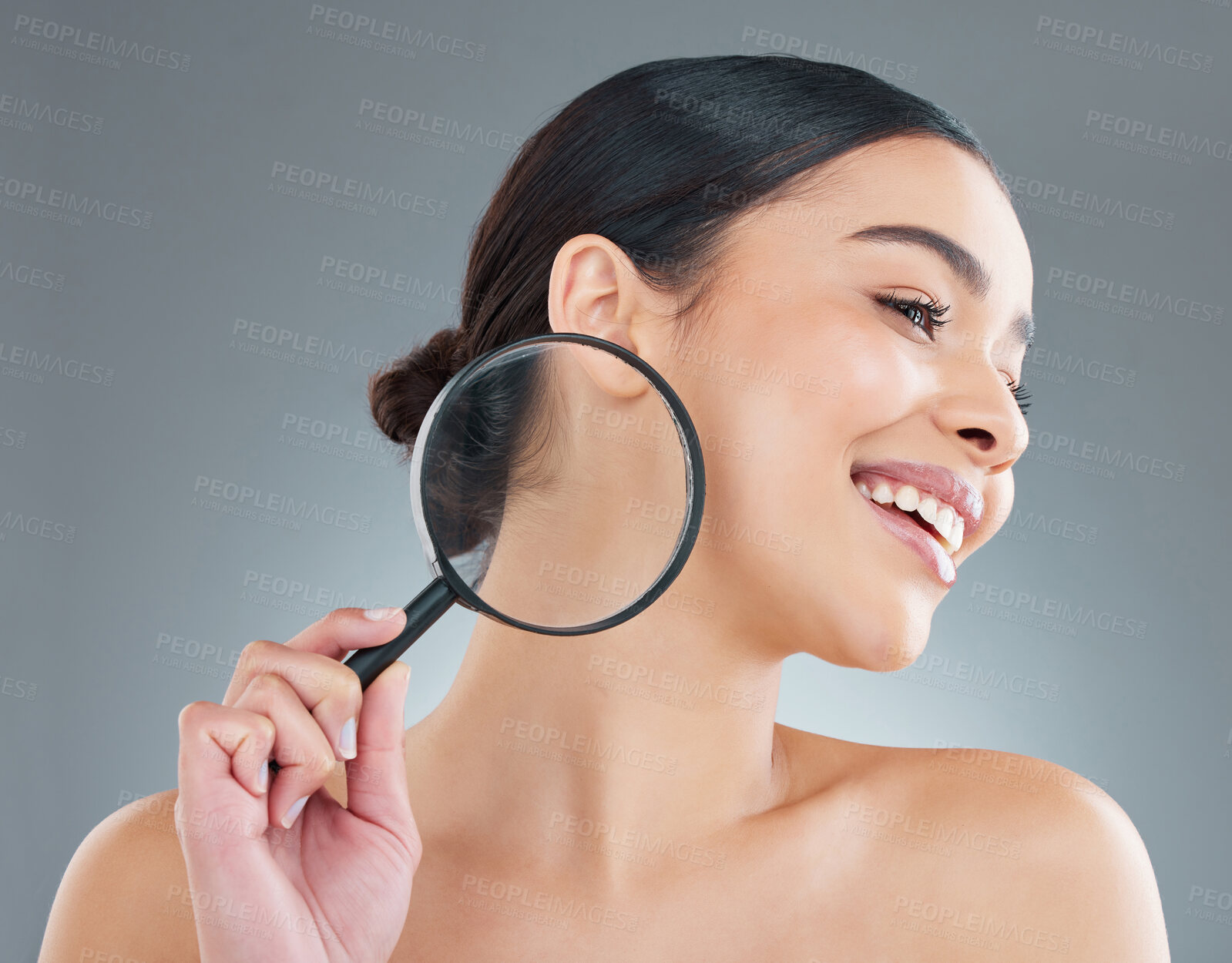 Buy stock photo Magnifying glass, beauty or happy woman in studio for skincare or cosmetology for shine on grey background. Inspection, search or face of girl with healthy glow or dermatology results for wellness