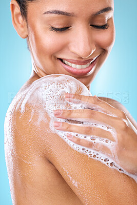 Buy stock photo Woman, soap and shower water cleaning shoulder in studio with wellness, happy or skincare beauty. Cosmetic, model and smile of young person in bathroom, isolated and dermatology by blue background