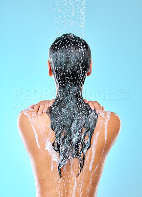 Buy stock photo Cropped shot of a woman washing her hair while taking a shower against a blue background