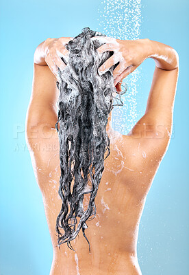 Buy stock photo Cropped shot of a woman washing her hair while taking a shower against a blue background