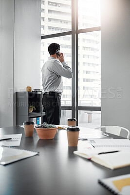 Buy stock photo Shot of an unrecognisable businessman standing alone in the office and using his cellphone