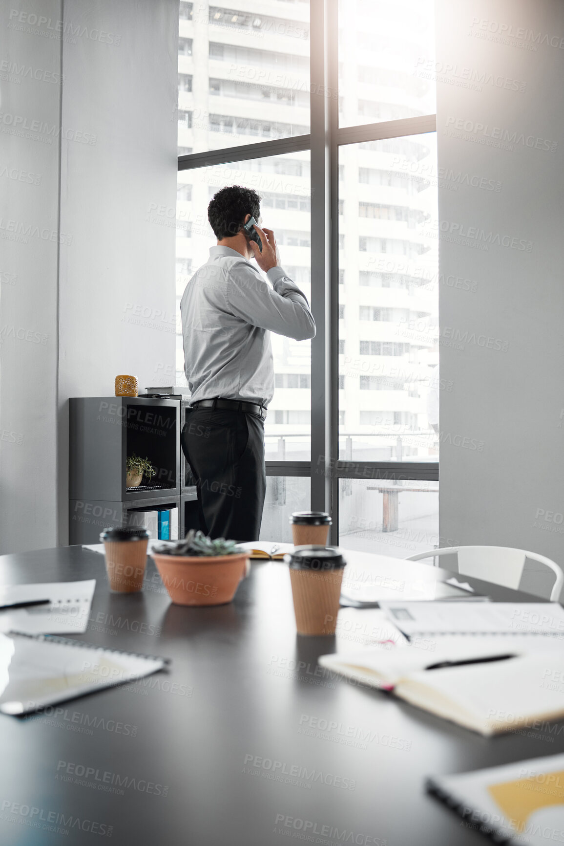 Buy stock photo Shot of an unrecognisable businessman standing alone in the office and using his cellphone