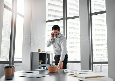 Buy stock photo Shot of an handsome mature businessman standing alone in the office and using his cellphone