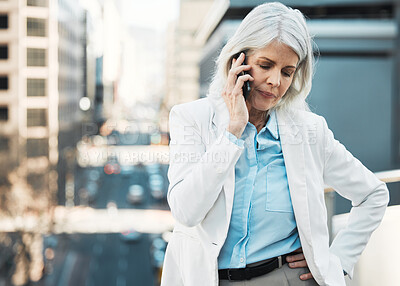 Buy stock photo Shot of a mature businesswoman standing alone outside and using her cellphone