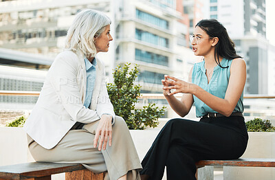 Buy stock photo Shot of two businesswomen sitting outside together and having a discussion